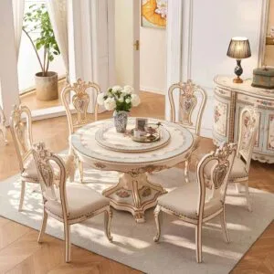 High-angle full view of a round marble dining table with a Lazy Susan and four tufted cream chairs on a rug.